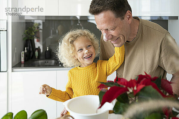 Glückliches blondes Mädchen backt mit Vater in der heimischen Küche