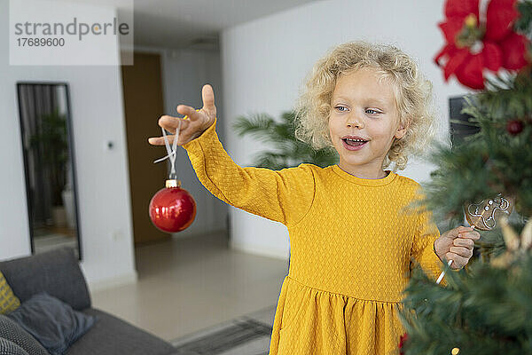 Blondes Mädchen schaut zu Hause auf Weihnachtsschmuck