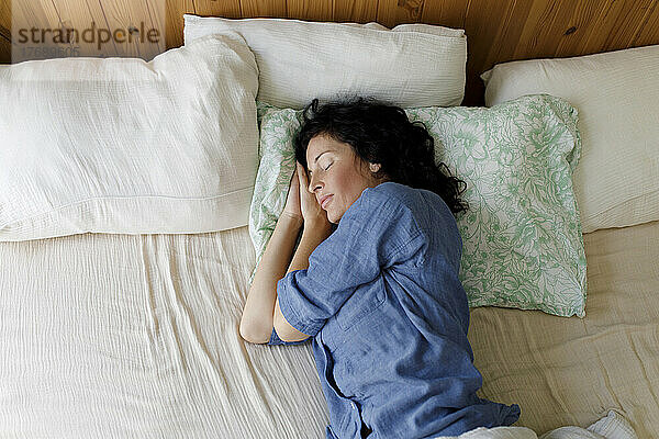 Frau mit geschlossenen Augen ruht zu Hause im Bett
