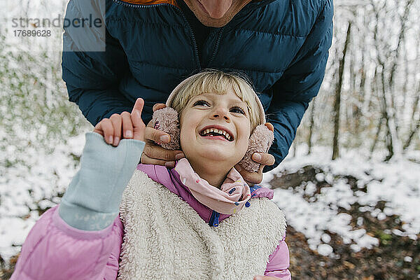 Verspieltes Mädchen mit Vater im Winterwald