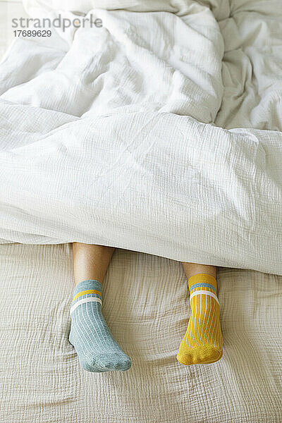 Woman wearing blue and yellow socks in bed