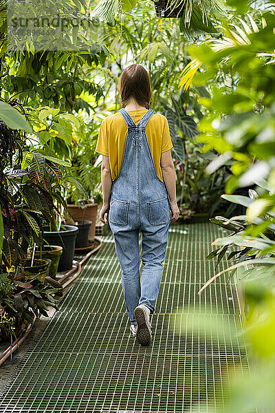 Junge Frau spaziert inmitten von Pflanzen im Garten