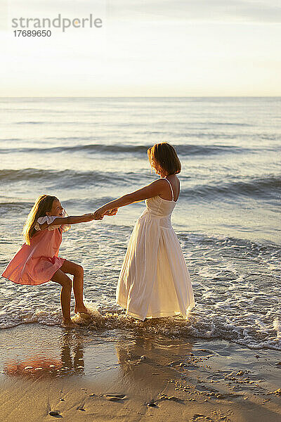 Glückliche Tochter  die mit Mutter am Strand spielt