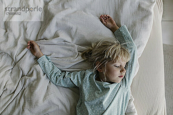 Girl with blond hair sleeping on bed at home