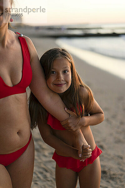 Glückliche Tochter hält die Hand ihrer Mutter am Strand