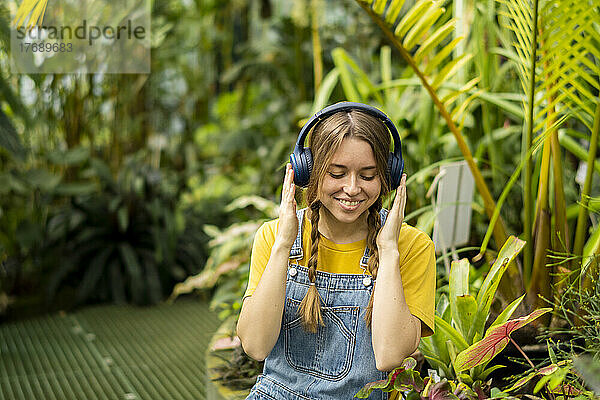 Glückliche Frau genießt Musik über kabellose Kopfhörer im Garten