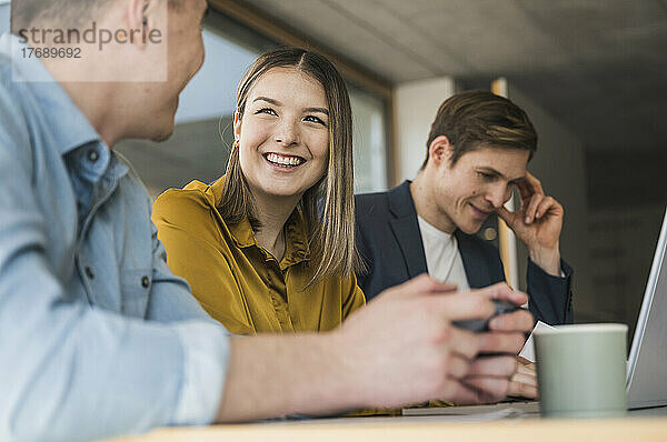 Lächelnde Geschäftsleute mit Smartphone und Laptop im Büro