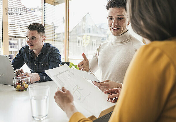 Junge Geschäftsleute diskutieren während einer Besprechung im Büro über ein Dokument