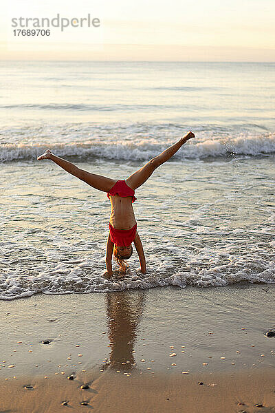 Girl doing handstand at beach