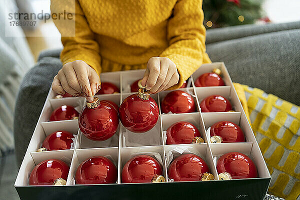 Mädchen mit einer Schachtel Weihnachtsschmuck zu Hause