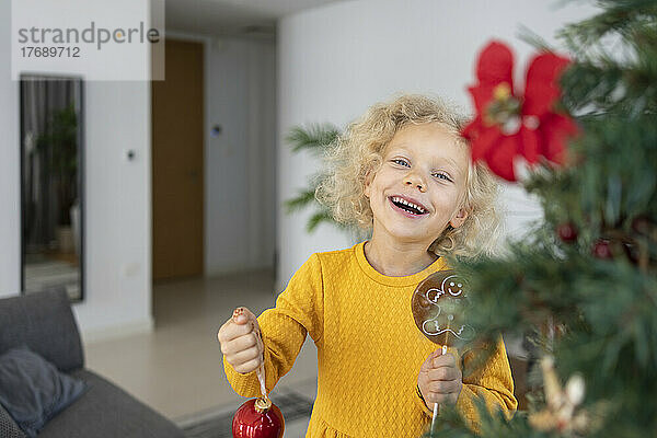 Cheerful blond girl with Christmas ornament at home
