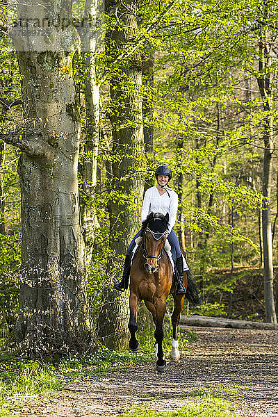 Lächelnde Frau reitet im Wald