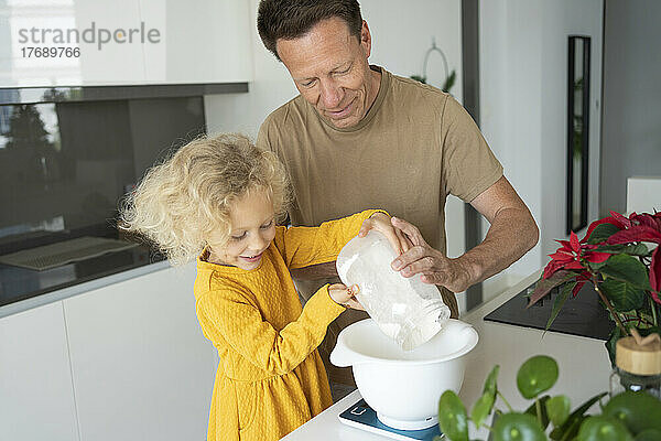 Lächelnder Vater und Tochter backen gemeinsam in der heimischen Küche