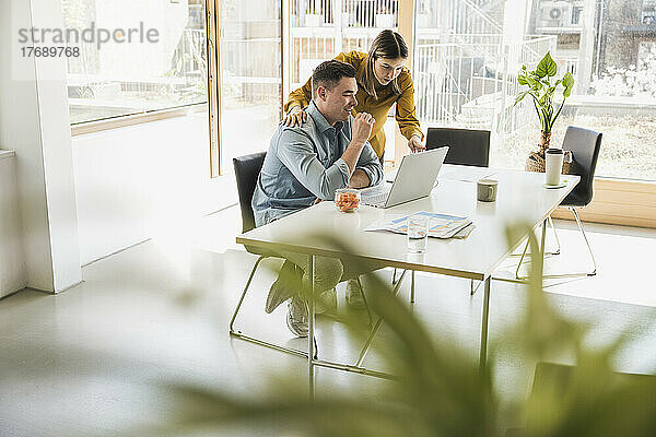 Geschäftsfrau und Geschäftsmann mit Laptop am Schreibtisch im Büro