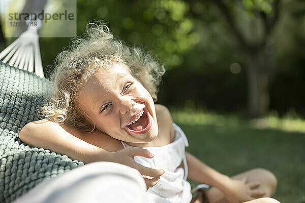 Happy girl leaning on hammock at garden
