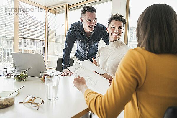 Glückliche junge Geschäftsleute während einer Besprechung im Büro