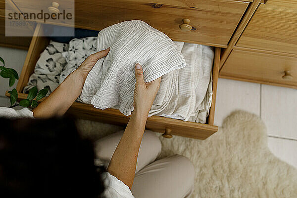 Hands of woman holding bedding at home