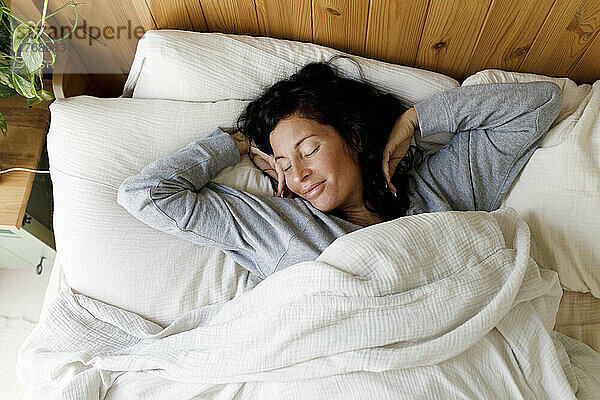 Smiling woman stretching in bed at home