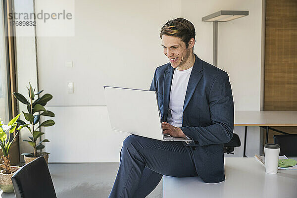 Lächelnder Geschäftsmann mit Laptop im Büro