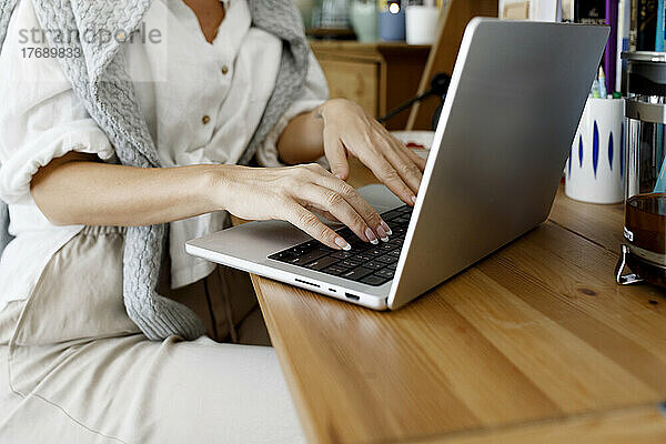 Hände einer Geschäftsfrau  die zu Hause einen Laptop benutzt