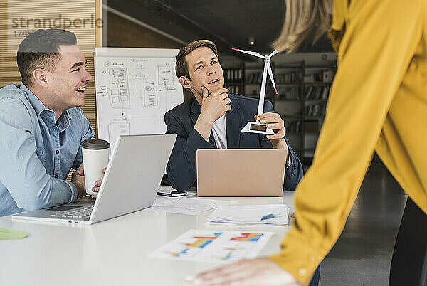 Geschäftsteam mit Windturbinenmodell bei einer Besprechung im Büro