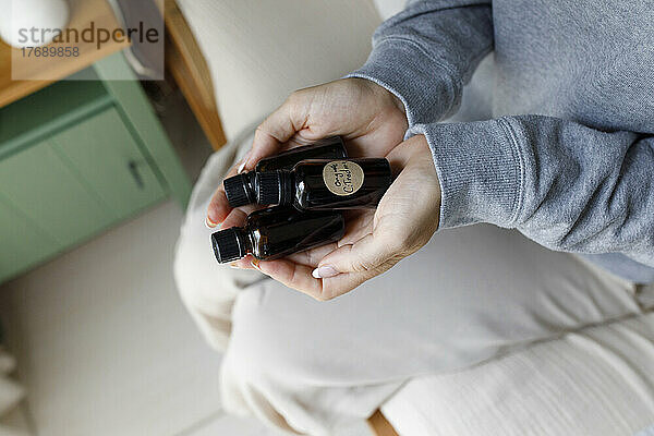 Frau hält Flaschen mit ätherischen Ölen zu Hause