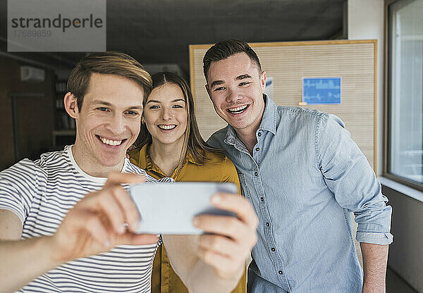 Glückliche Geschäftsleute  die im Büro ein Selfie machen