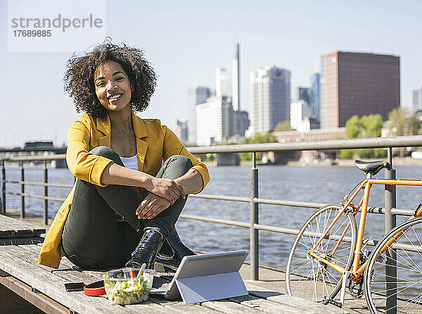 Junge Geschäftsfrau mit Essen und Laptop am Main