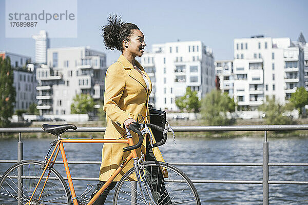 Geschäftsfrau fährt an einem sonnigen Tag mit dem Fahrrad am Main entlang