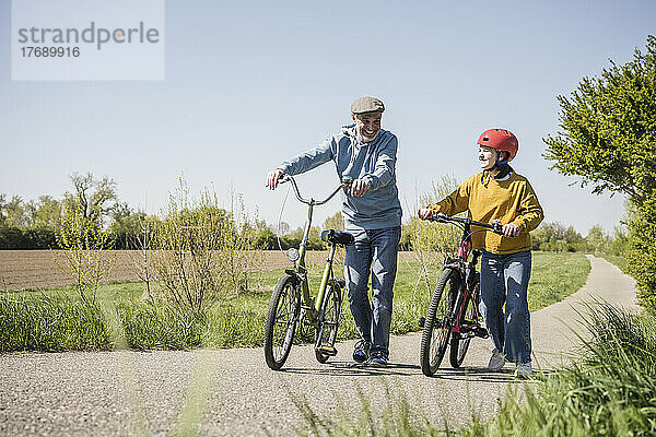 Glücklicher Großvater und Enkelin  die mit dem Fahrrad unterwegs sind