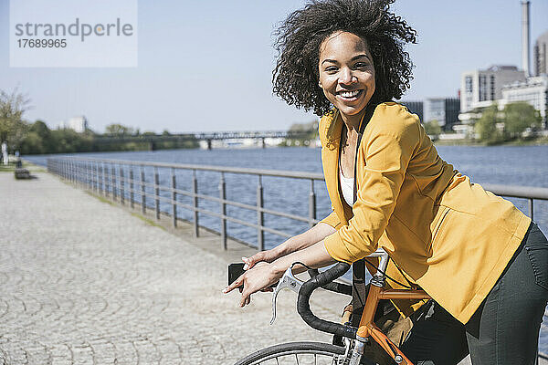 Fröhlicher Pendler stützt sich auf sein Fahrrad am Main