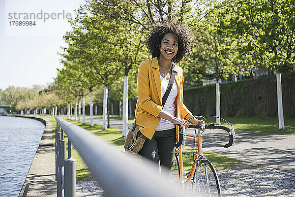 Glückliche Geschäftsfrau mit Fahrrad am Main
