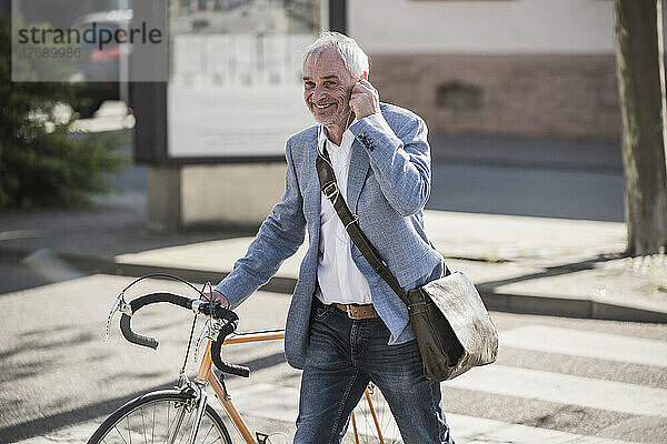 Glücklicher Geschäftsmann  der an einem sonnigen Tag mit dem Fahrrad spaziert