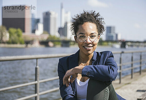 Lächelnde Geschäftsfrau mit Brille an einem sonnigen Tag