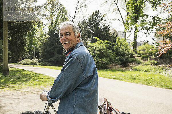 Glücklicher älterer Mann  der an einem sonnigen Tag Fahrrad fährt