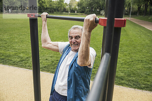 Aktiver älterer Mann trainiert an der Gymnastikstange im Park
