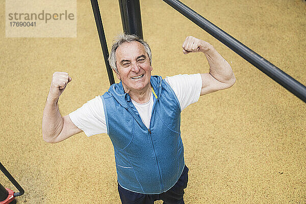 Confident senior man flexing muscles at park
