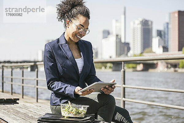 Lächelnde Geschäftsfrau mit Tablet-Computer auf Bank sitzend