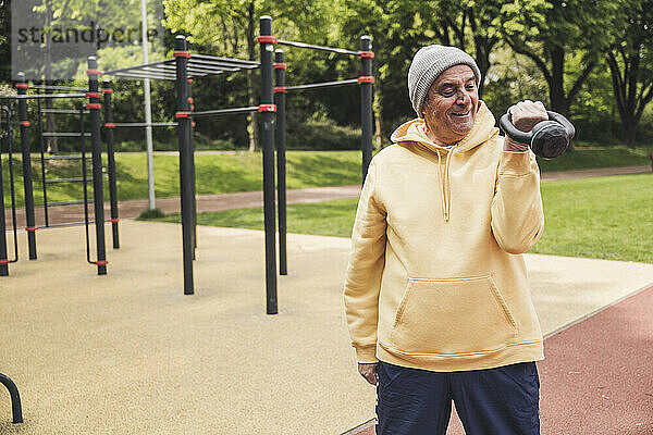 Lächelnder älterer Mann trainiert mit Kettlebell im Park