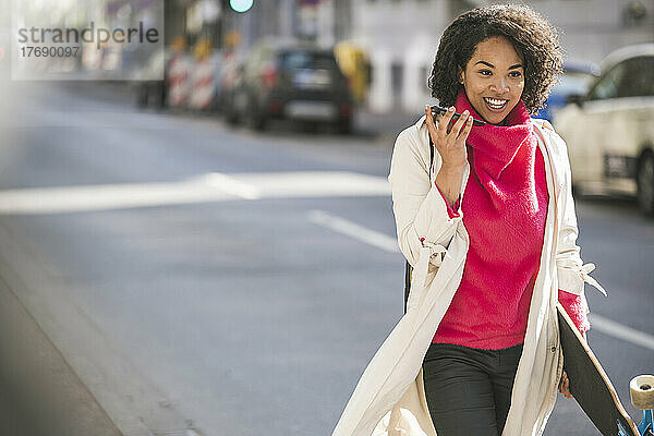Lächelnde Geschäftsfrau  die ihr Smartphone auf der Straße benutzt