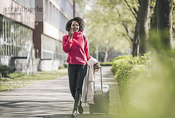 Geschäftsfrau läuft mit Rollgepäck auf Fußweg