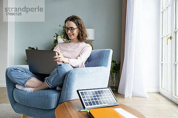 Lächelnde Geschäftsfrau  die im Wohnzimmer am Laptop arbeitet