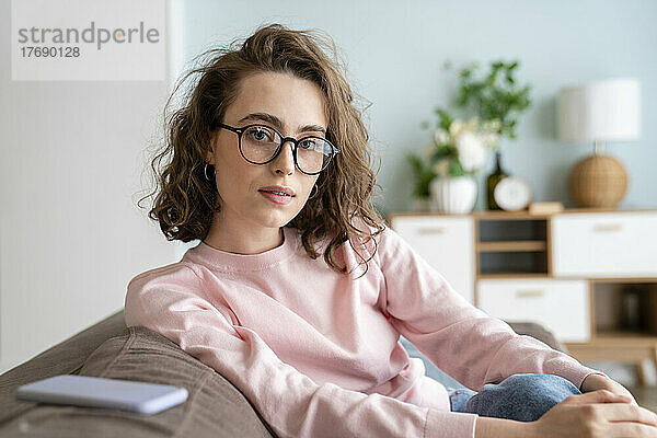 Junge Frau mit Brille im Wohnzimmer