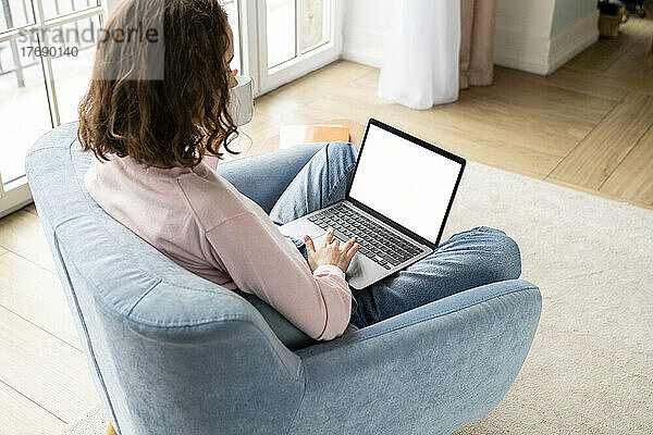 Junge Geschäftsfrau tippt auf dem Laptop und arbeitet zu Hause