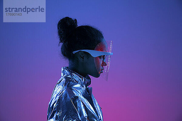 Junge Frau mit futuristischer Smart-Brille vor mehrfarbigem Hintergrund