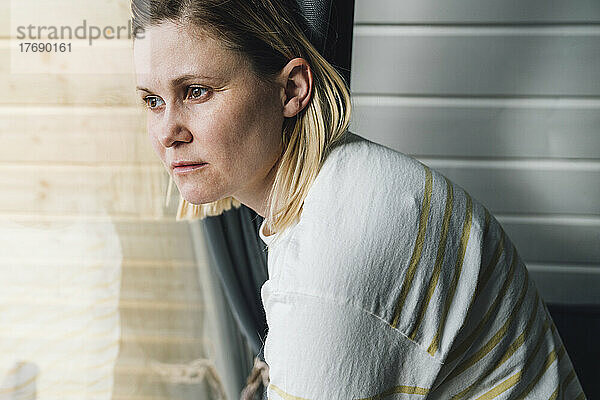Traurige Frau  die zu Hause aus dem Fenster schaut