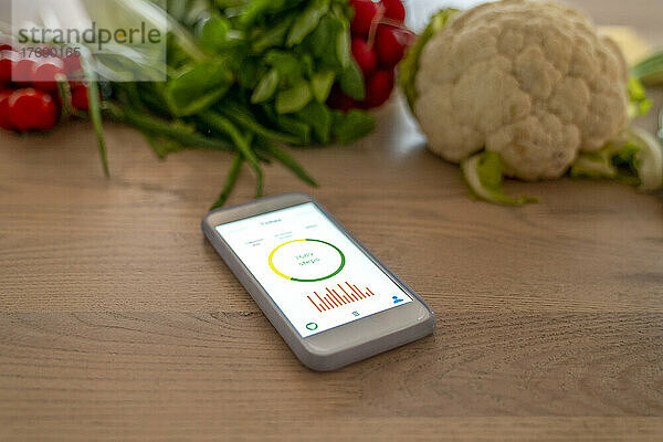 Smartphone mit Gesundheits-Tracker auf dem Gerätebildschirm von Gemüse