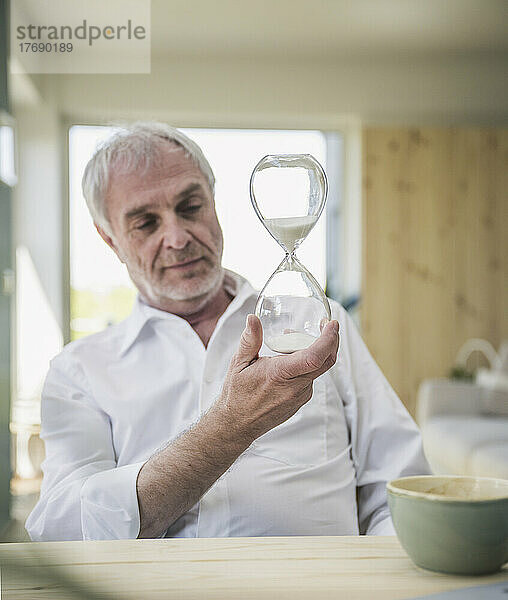 Retired senior man looking at hourglass