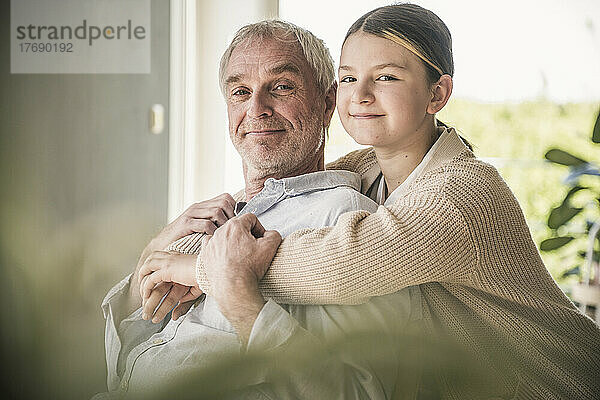 Glückliche Enkelin umarmt Großvater zu Hause