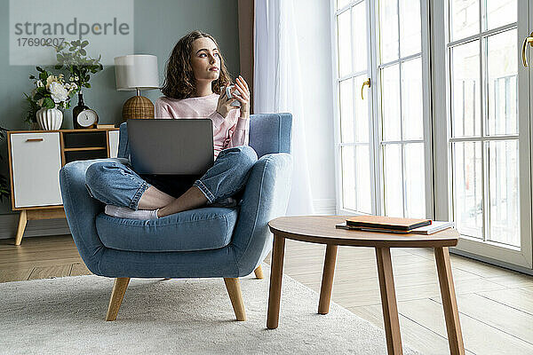 Nachdenkliche Geschäftsfrau mit Laptop zu Hause